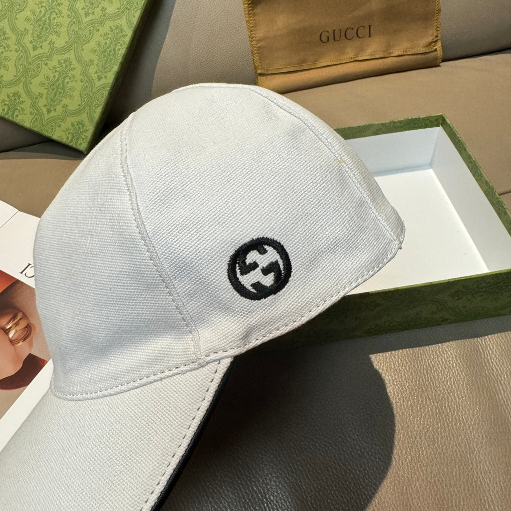 Gucci white cap close-up with black GG emblem on crown.