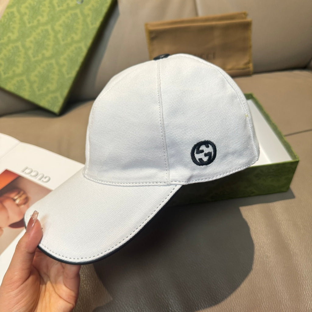 Gucci white cap with black GG emblem and curved brim.