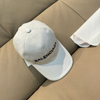 White Balenciaga baseball cap with embroidered logo and curved brim.