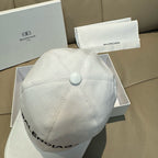 White Balenciaga baseball cap with button crown and stitched paneling.