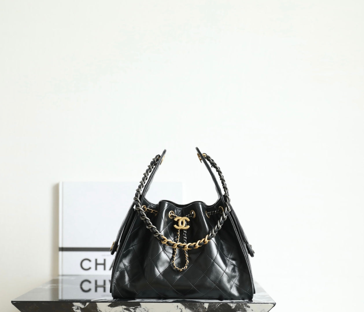 Chanel quilted leather bag in dark tone with gold chain handles and tassel charms