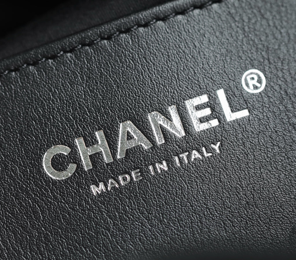 Chanel leather label with embossed “MADE IN ITALY” text on dark finish