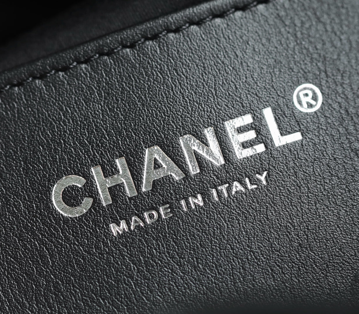 Chanel leather label with embossed “MADE IN ITALY” text on dark finish