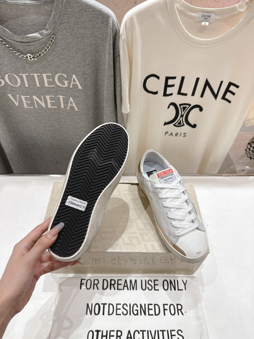 Golden Goose luxury sneakers: white outsole with textured tread, held above the display
