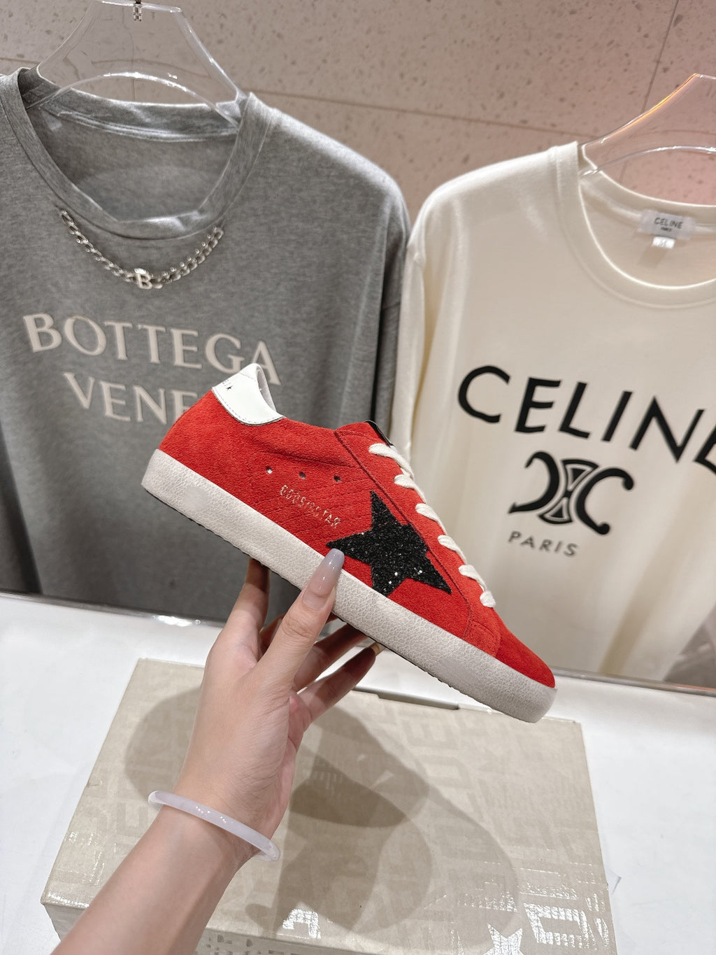 Golden Goose red suede sneakers with white laces and black star on side, shoe close-up