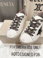 Close view of white sneakers with red collar, leopard-pattern laces, and black star detail