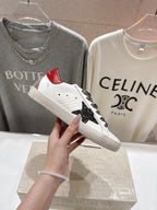 White sneaker showing red heel tab, leopard-print laces, and black star side panel