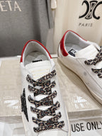 White sneaker close-up with red heel lining, leopard lace overlay, and patterned tongue