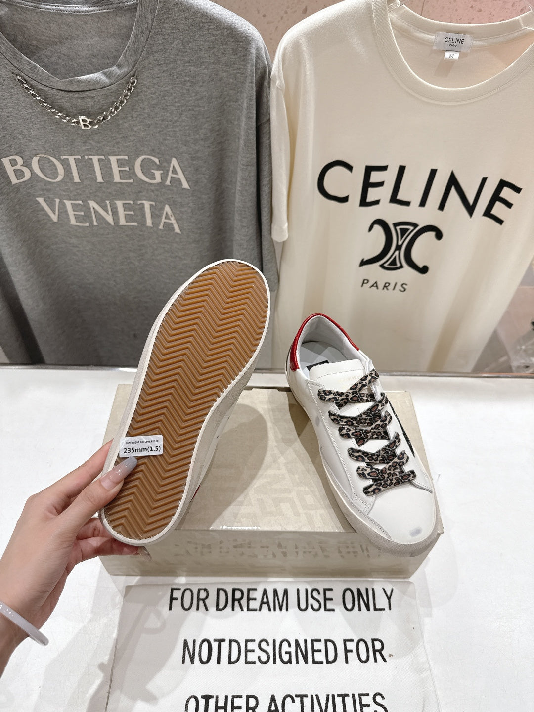 White sneakers with leopard laces; one shows textured tan outsole bottom