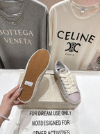 Lilac and white sneakers with star detail, outsole view held by hand