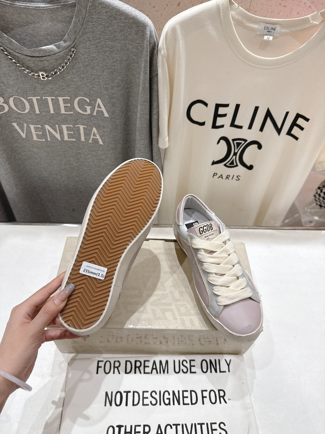 Lilac and white sneakers with star detail, outsole view held by hand