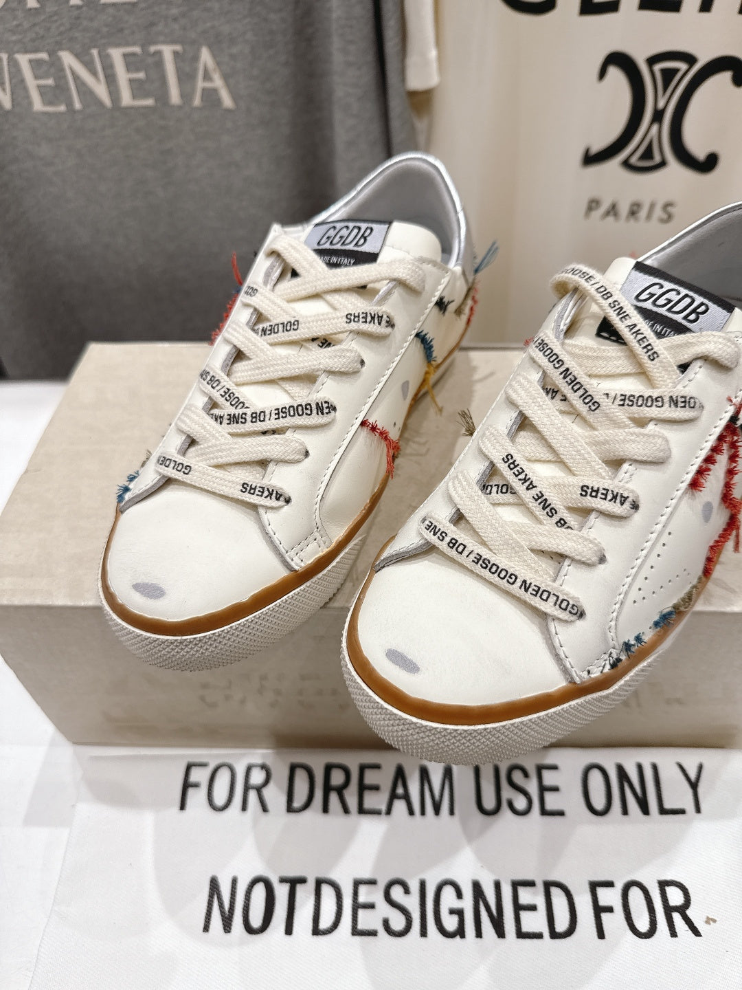 White lace-up sneakers with side panels, printed tongue labels, and tan gum soles