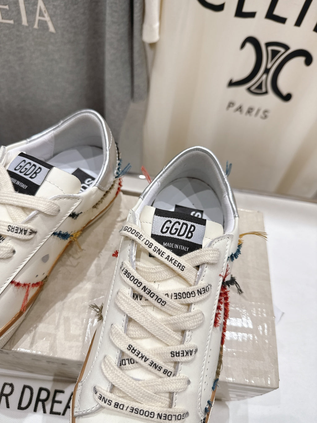 Close-up of two white sneakers from front, showing lace-up and side logo patch