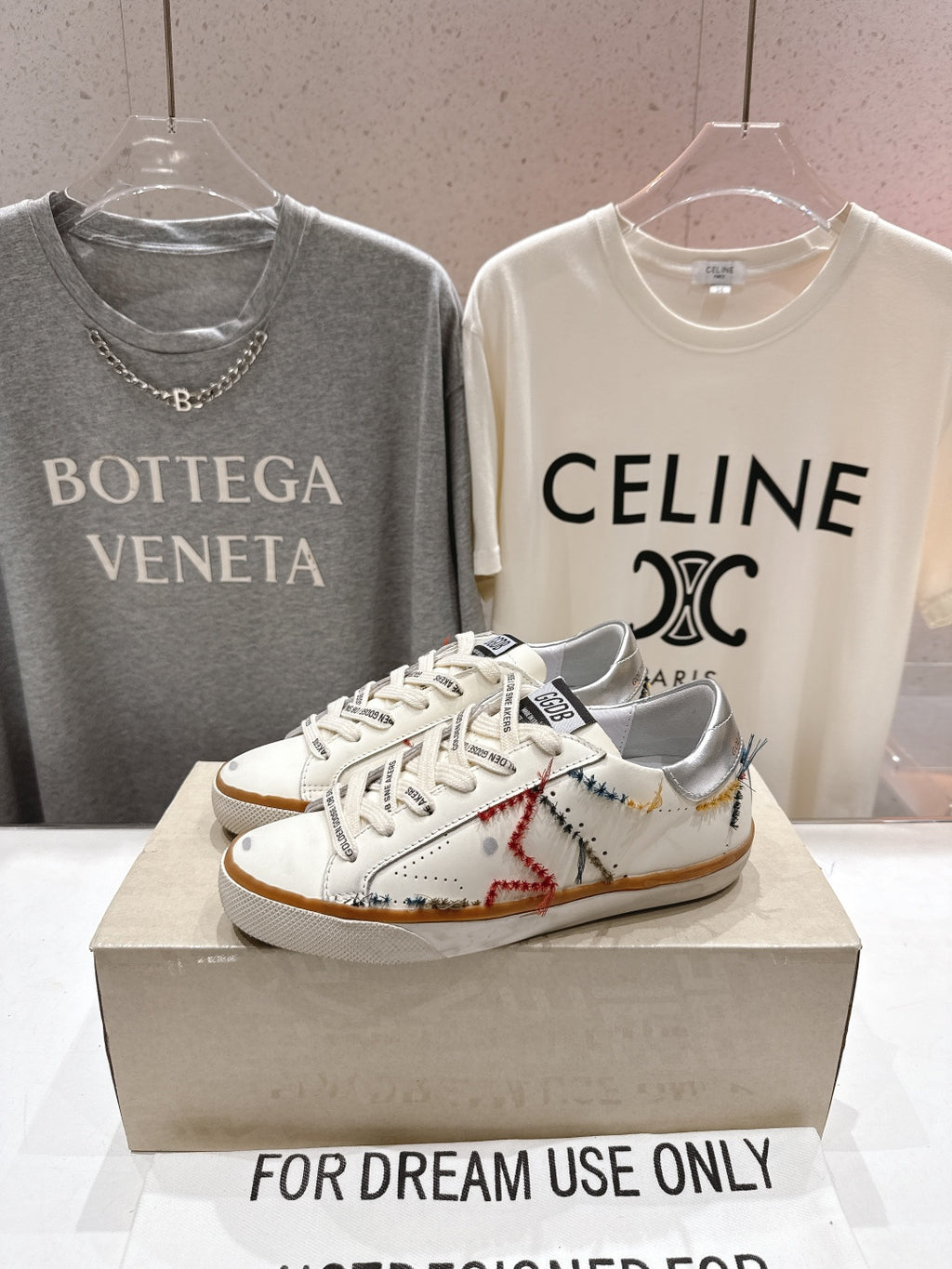 White lace-up sneakers with brown stitching accents and tan gum outsole, on display