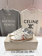 White lace-up sneakers with brown stitching accents and tan gum outsole, on display