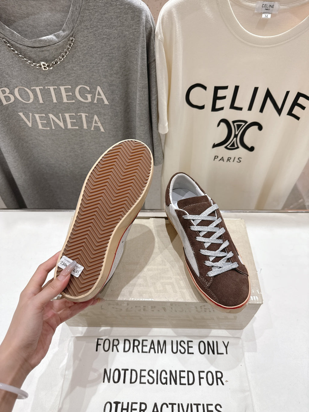 Brown suede sneakers showing patterned gum outsole, with white laces and red trim.