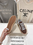 Brown suede sneakers showing patterned gum outsole, with white laces and red trim.