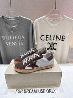 Brown, white and red-trim sneakers with white laces on display box, single shoe visible.