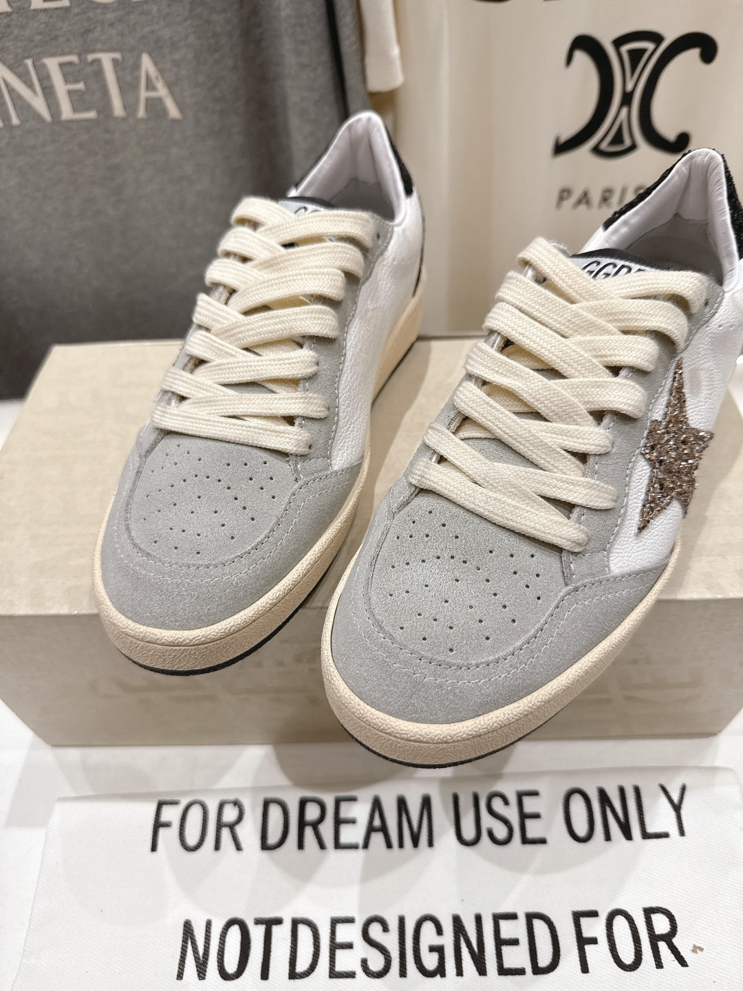 Front view pair of light gray and white sneakers with cream laces