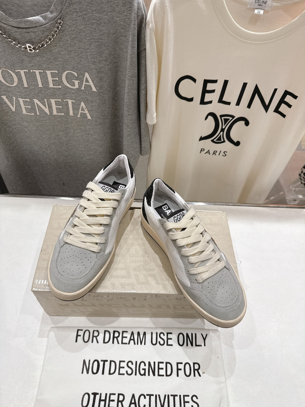 Pair of light gray and white sneakers with cream laces and logo patch at heel