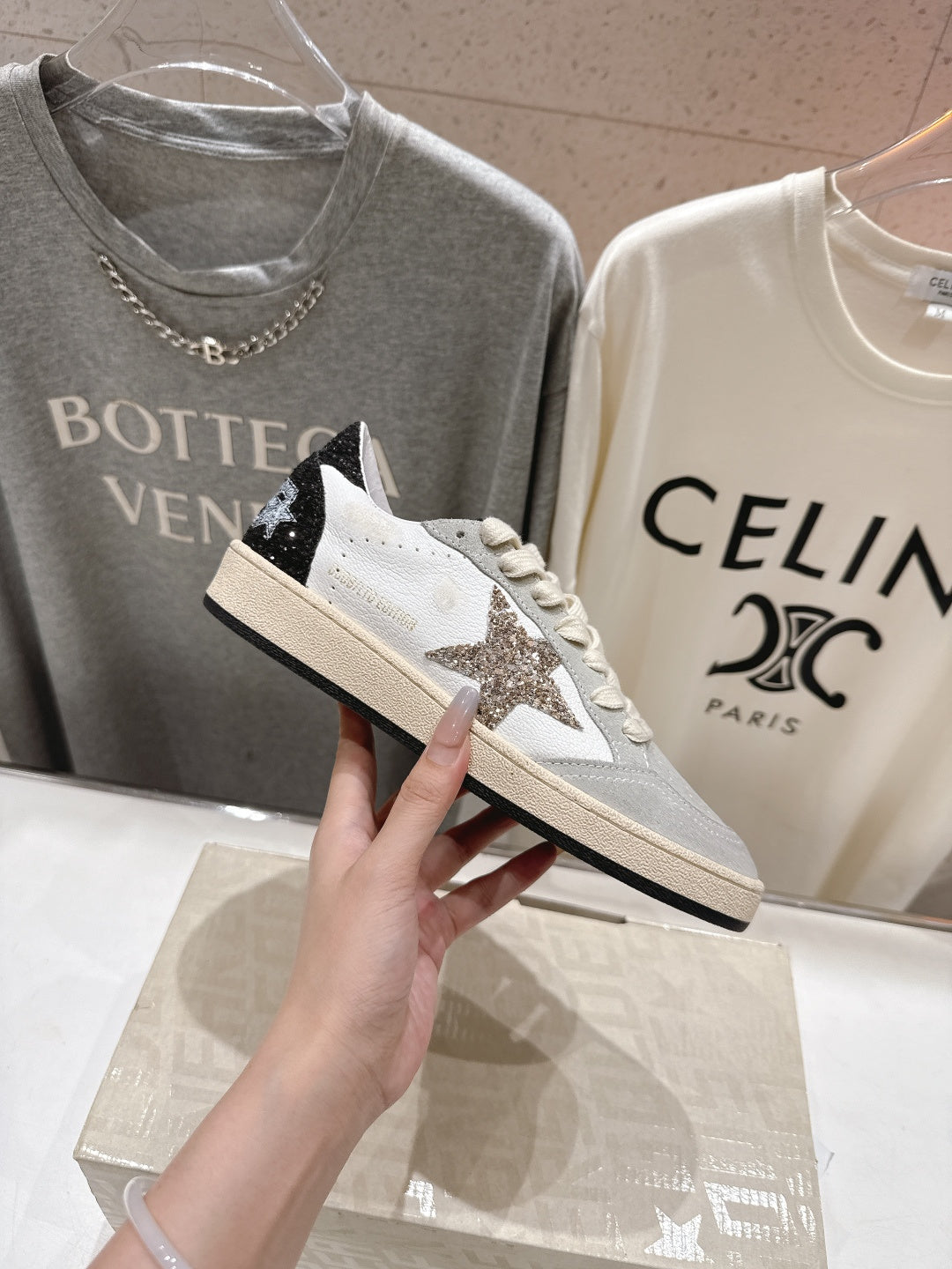 White sneaker with light gray toe, cream laces, and black star patch
