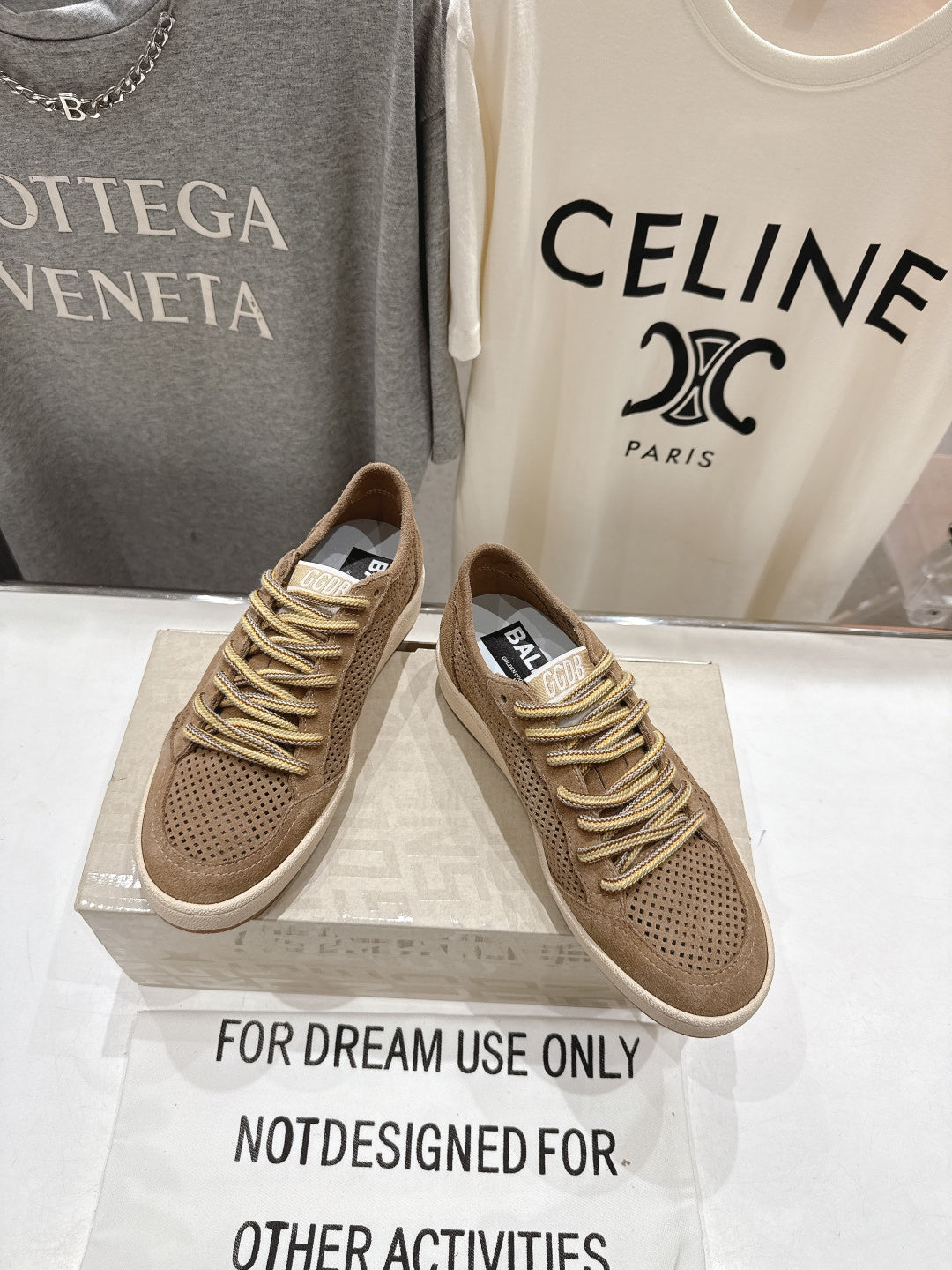 Side view tan low-top sneakers, perforated upper and gold laces with white sole