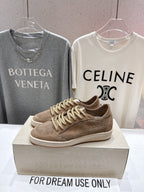 Tan perforated low-top sneakers with braided gold laces on display box