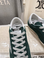 Front view of dark green suede Golden Goose sneaker with white laces and label on tongue