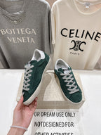 Hand holding dark green suede Golden Goose sneakers with white laces and white rubber sole