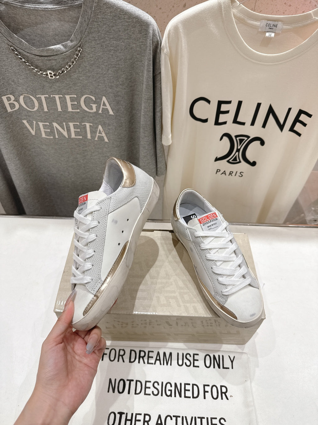 Golden Goose luxury sneakers: white pair with green star side patch and gold heel tab