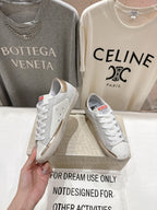 Golden Goose luxury sneakers: white pair with green star side patch and gold heel tab