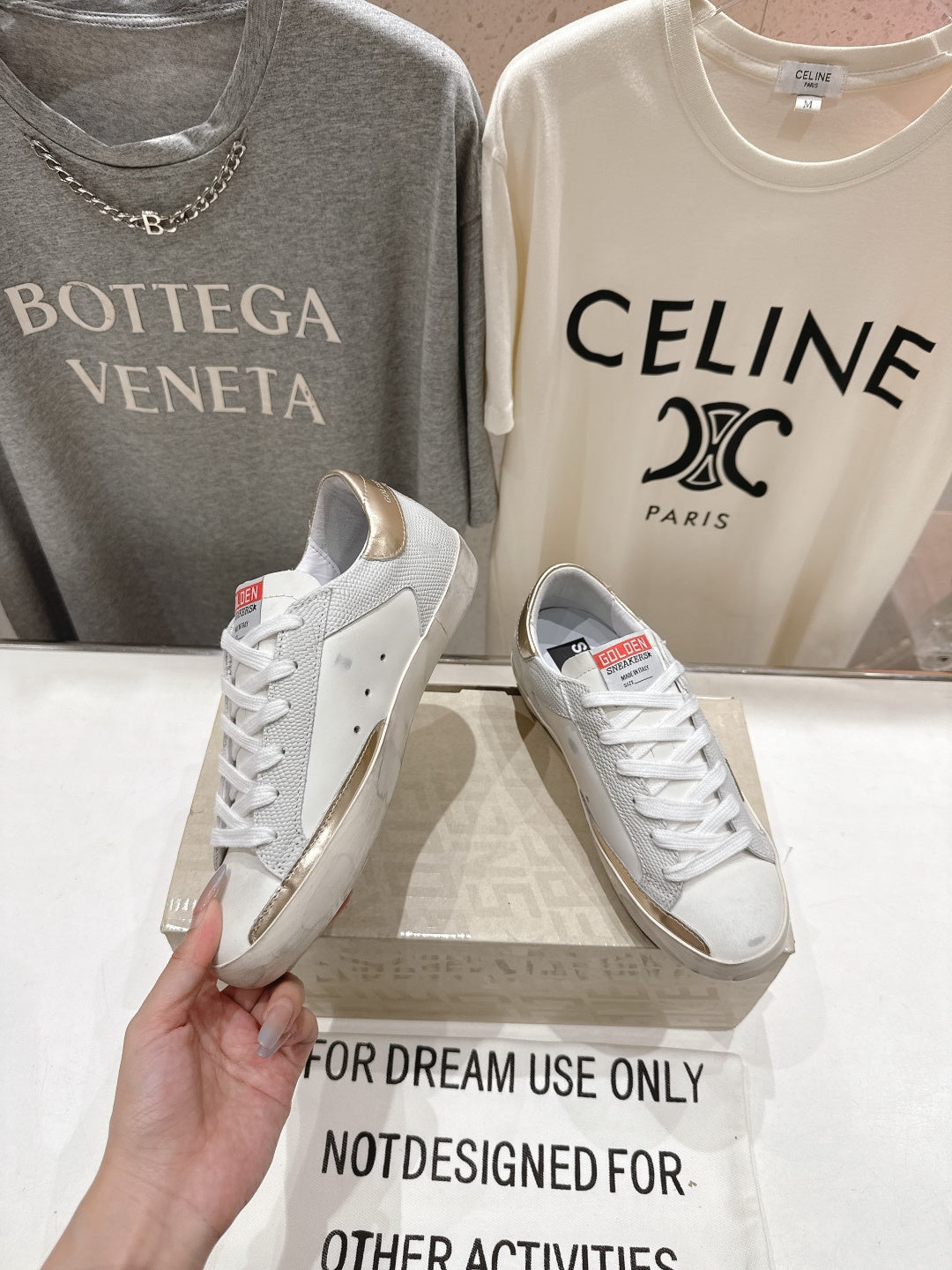 Golden Goose luxury sneakers: white pair with green star side patch and gold heel tab