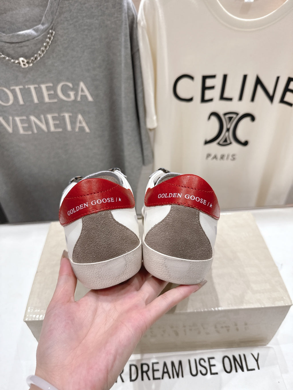Back view of white sneakers with red heel lining held in hand