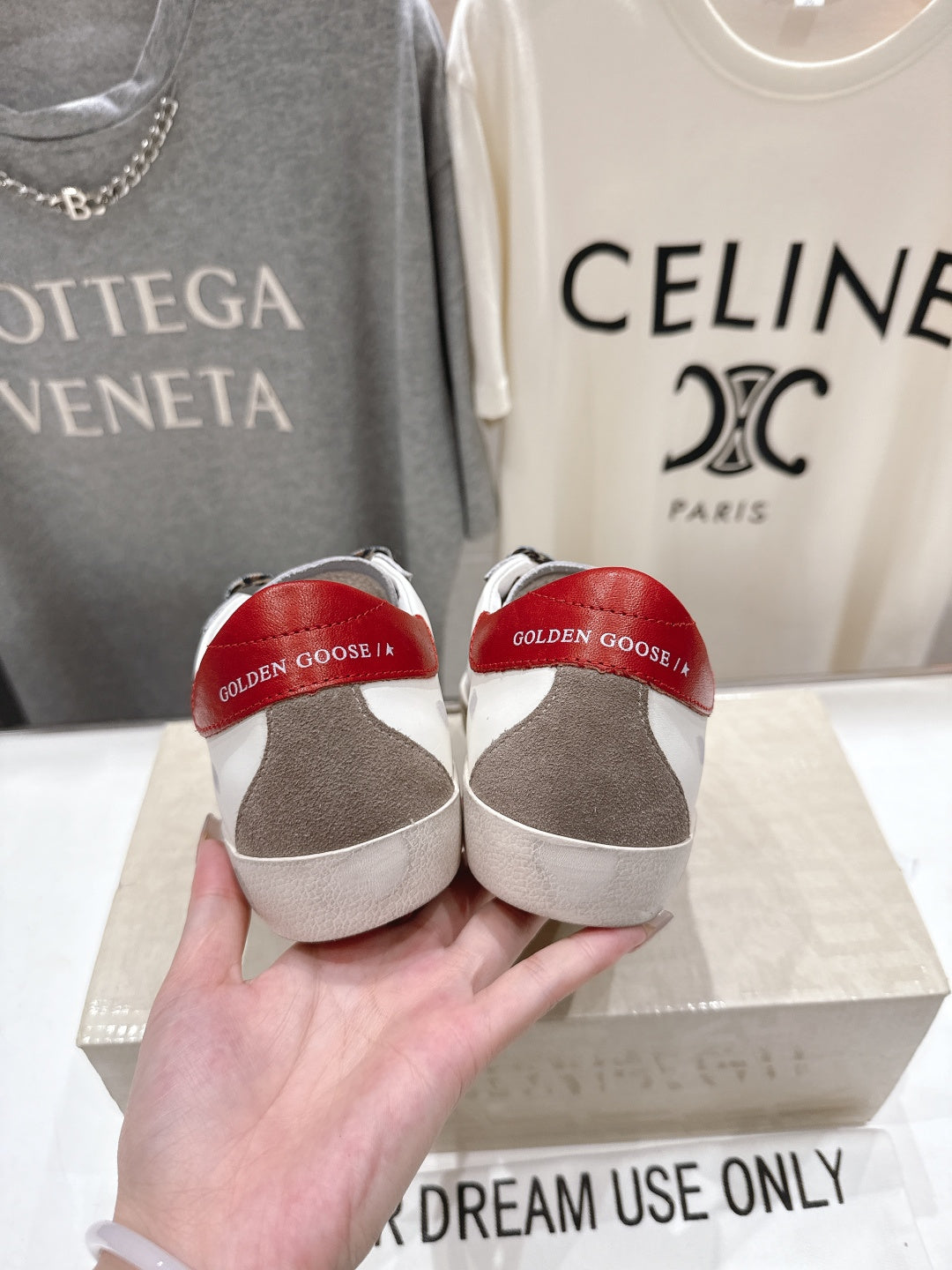 Back view of white sneakers with red heel lining held in hand