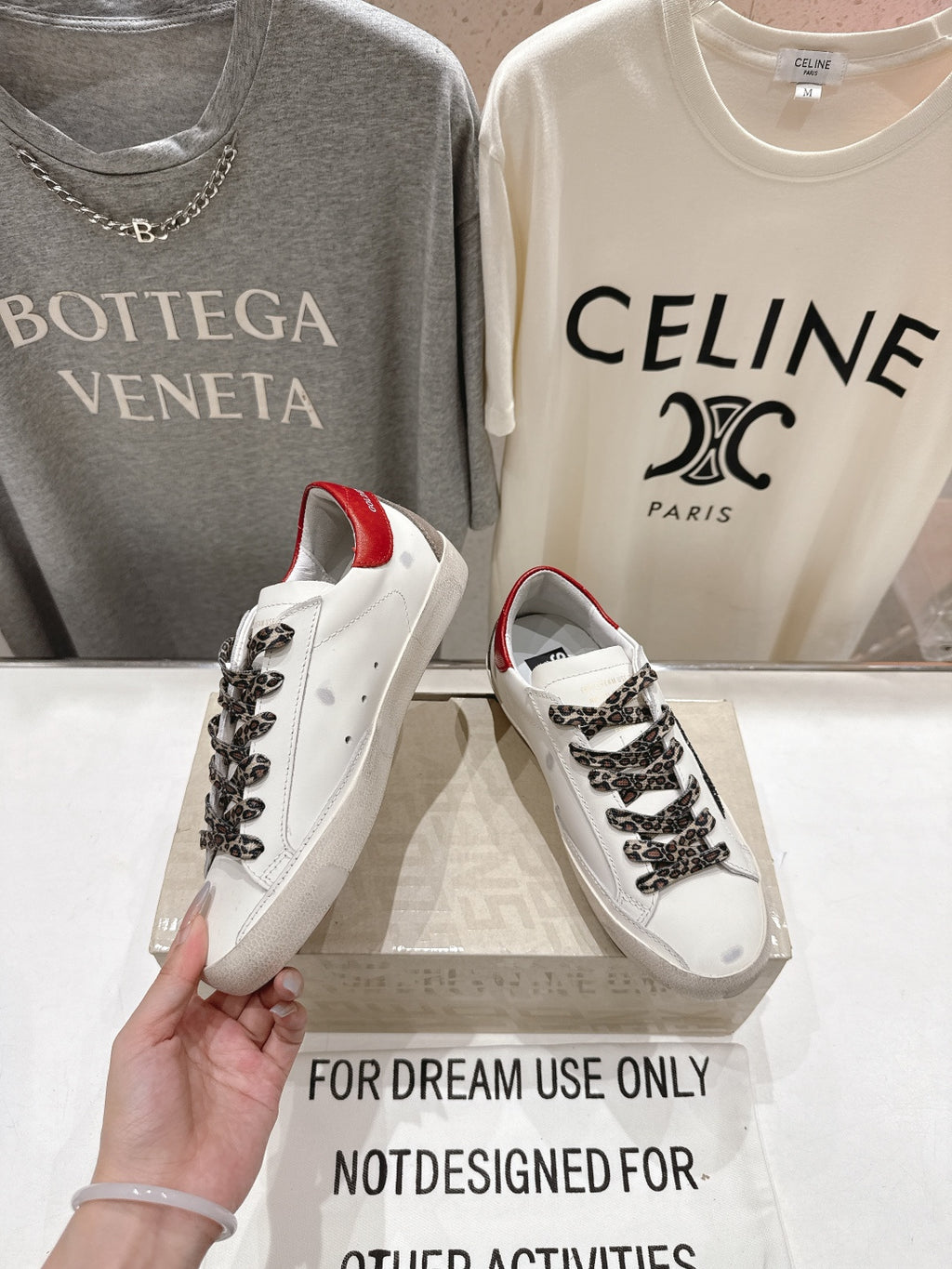 Handheld white sneaker with red heel lining, leopard lace overlay, and black star accent