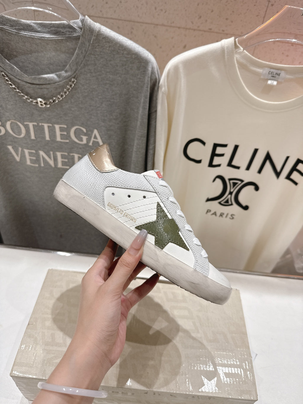 Golden Goose luxury sneakers: white side view with gold heel tab and green star patch