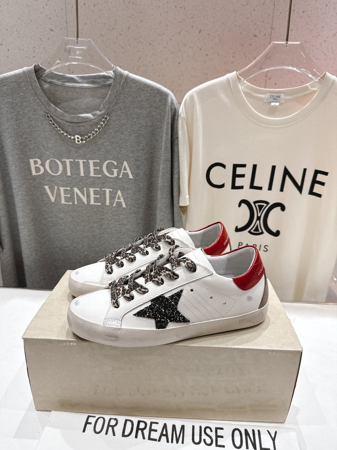 White low-top sneakers on a box, featuring leopard-pattern laces and black star patch