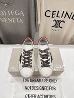 Pair of white sneakers with red trim, leopard-pattern laces, and black star detail