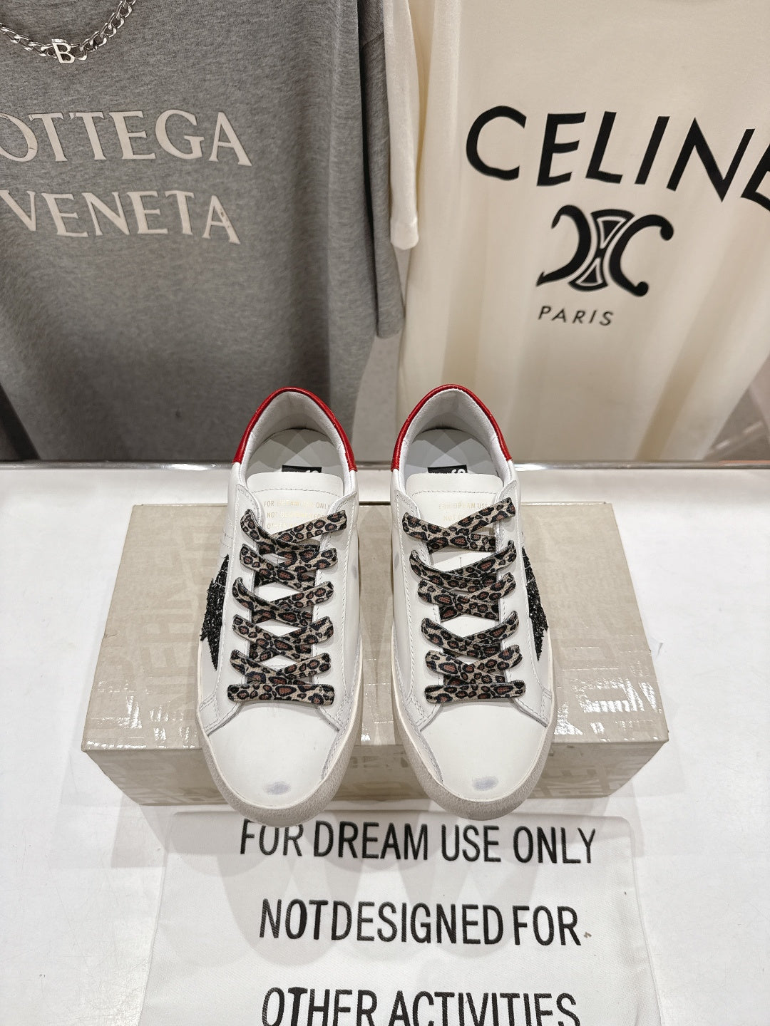Pair of white sneakers with red trim, leopard-pattern laces, and black star detail