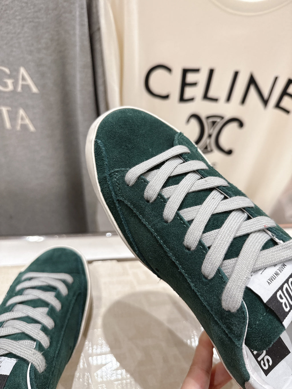 Close-up of dark green suede Golden Goose sneaker upper with white lace-up and trim