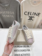 Lilac and white lace-up sneakers with star detail, side view held in hand