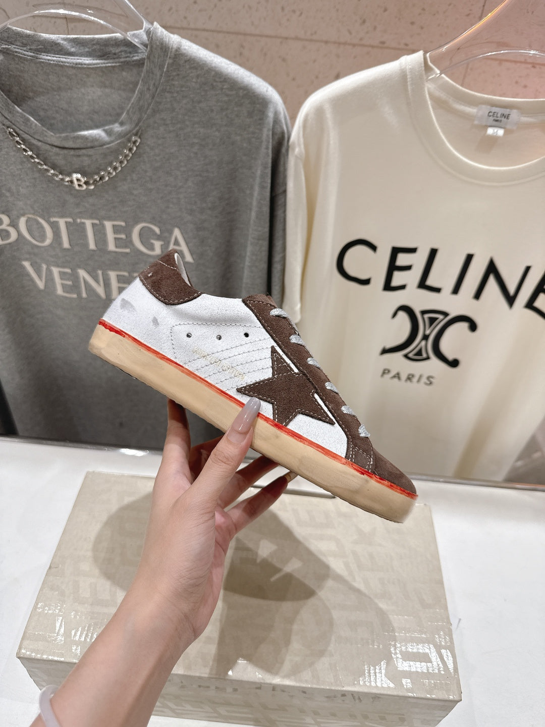 Close-up of brown and white lace-up sneakers with white laces and red sole trim.