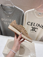 Close-up tan suede low-top sneaker with perforated sides and gold laces