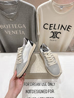 Light gray and white sneakers with cream laces, angled view in hand