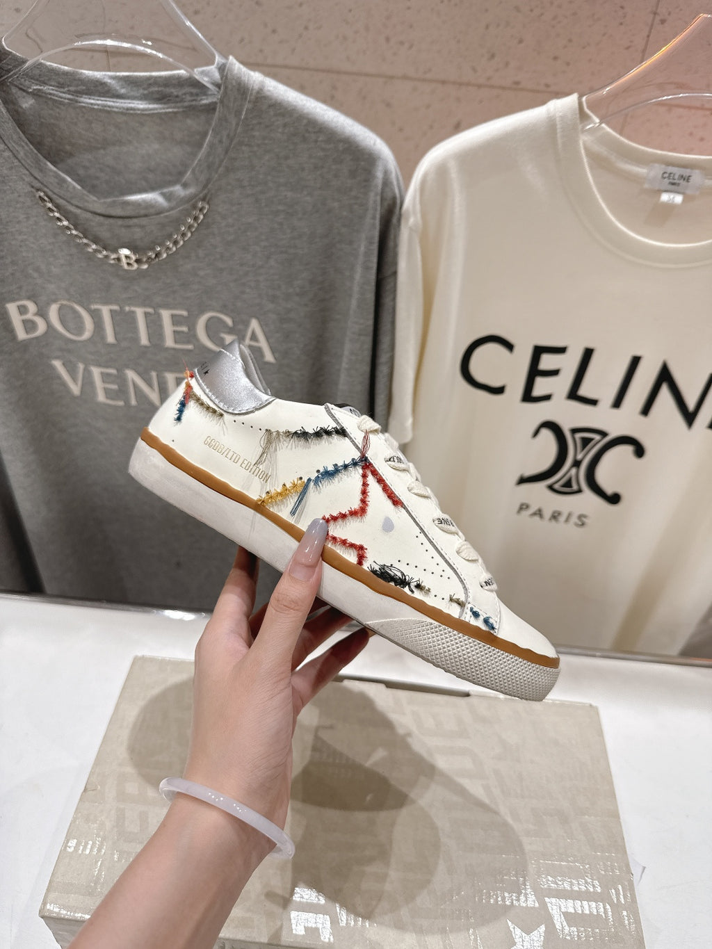 White sneaker close-up with multicolor stitched side details and tan gum outsole