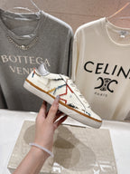 White sneaker close-up with multicolor stitched side details and tan gum outsole