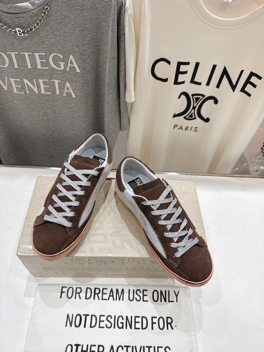 Pair of brown and white lace-up sneakers with white laces, angled side view on a box.