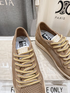 Tan low-top sneakers close-up, gold laces and tongue label