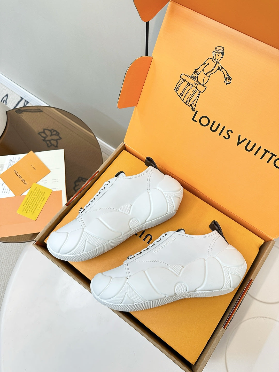 White lace-up sneakers with dark heel patches shown in an open shoe box
