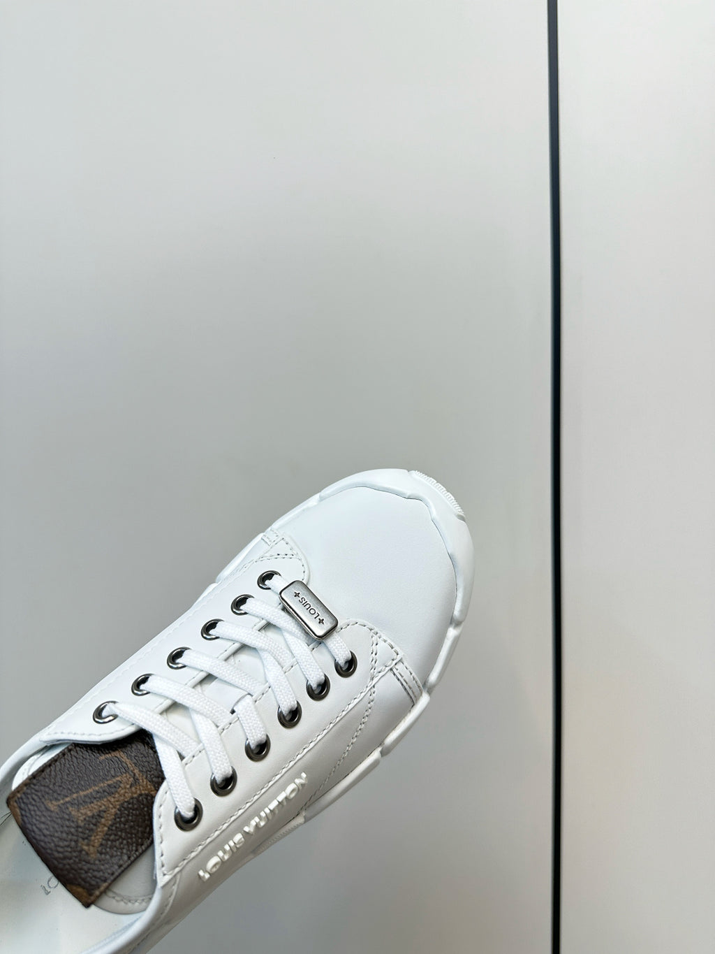 White sneaker side view with dark interior lining and lace-up eyelets